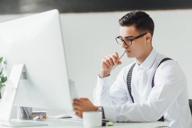 gazete ve bilgisayar ile işyerinde bir şey yazma işadamı