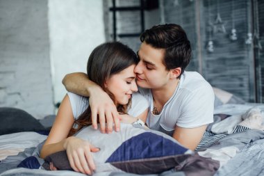 Genç çekici çift evde yatakta romantik zaman