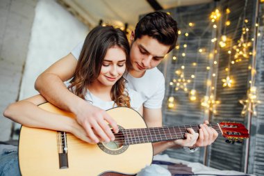 Evde akustik gitar oynarken yakışıklı genç adam öğretim kadın 