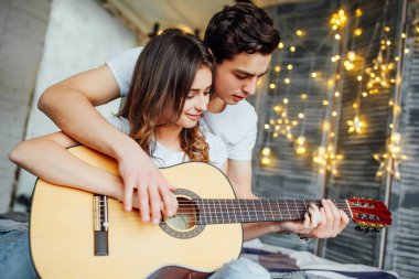 Evde akustik gitar oynarken yakışıklı genç adam öğretim kadın 