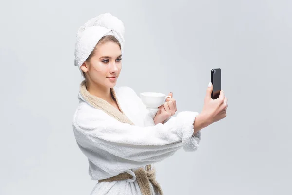 Kobieta Odpoczywa Domu Szatę Ręcznikiem Głowie Pomocą Smartfona Białym Kubkiem — Zdjęcie stockowe