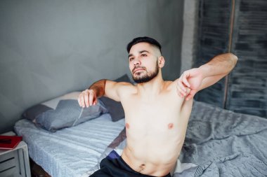 Sakal ile çekici adam yatakta oturan sabah egzersiz yapıyor