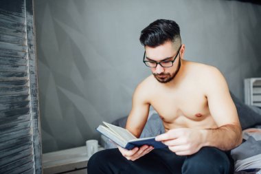 Evde yatakta yatarken ilginç kitap okuma rahat genç adam