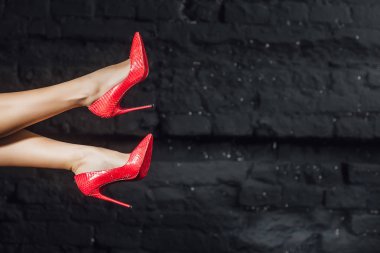 Siyah arka planda kırmızı ayakkabılar uzun güzel bacaklar ile moda kadın