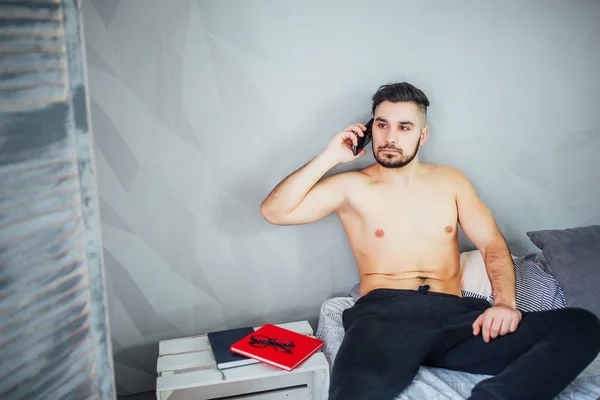 Yatakta Yatarken Akıllı Telefonda Konuşan Genç Adam — Stok fotoğraf