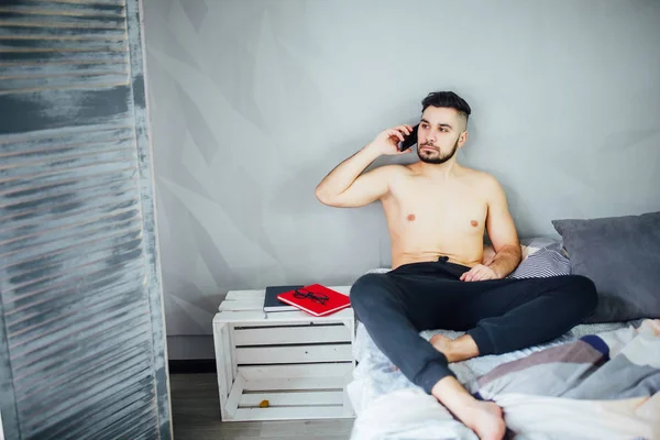 Junger Mann Liegt Auf Bett Und Telefoniert Mit Smartphone — Stockfoto