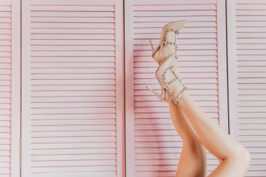 Pembe arka planda çıplak ayakkabılar ince kadın bacaklar