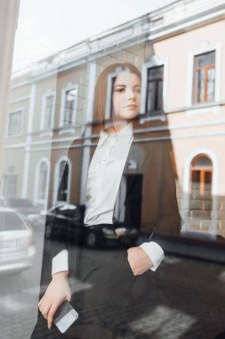 Kafede akıllı telefonu olan genç bir iş kadını, seçici odaklı.