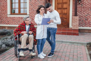 Hemşire ile Oğlu tekerlekli sandalyede yaşlı adam hakkında konuşuyor ve sonuçları bakıyor