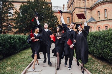 Diploma tutan akademik elbiselerde başarılı mezunlar