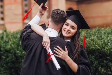 Üniversite nin yanında duran ve kucaklayan elleri diploması olan mantomezunları 