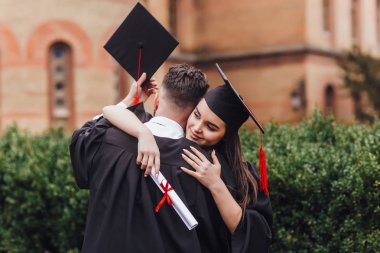 Üniversite nin yanında duran ve kucaklayan elleri diploması olan mantomezunları 