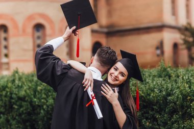 Üniversite nin yanında duran ve kucaklayan elleri diploması olan mantomezunları 