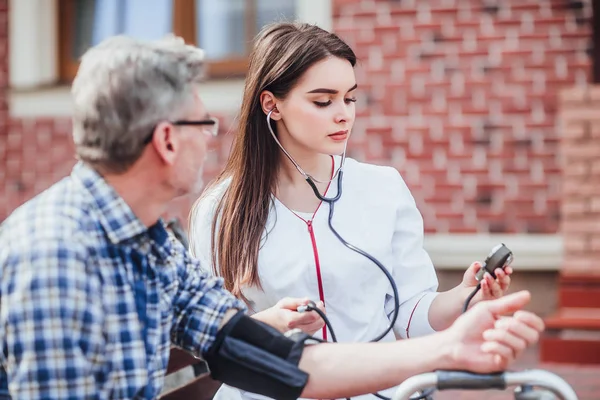 Ošetřovatelka Měří Puls Starého Muže Zahradě Kliniky — Stock fotografie