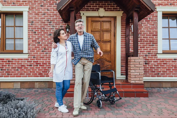 nurse helping man with rehabilitation near clinic