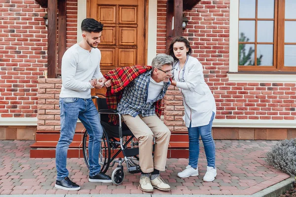 Hijo Ayudando Padre Levantarse Silla Ruedas Enfermera Tomados Mano Cerca — Foto de Stock