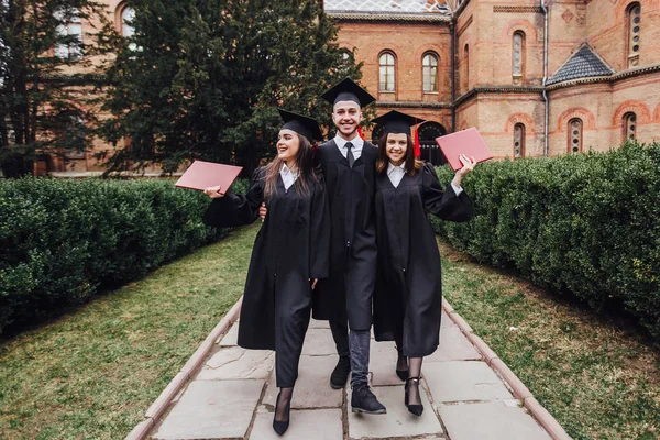 Üniversite bahçesinde yürüyen diplomalı başarılı mezunlar