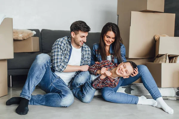 Happy family with cardboard boxes plying with son