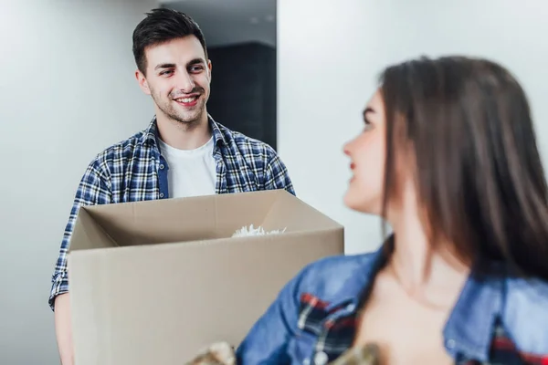 Focus at happy man with box in hands in new house, woman in foreground