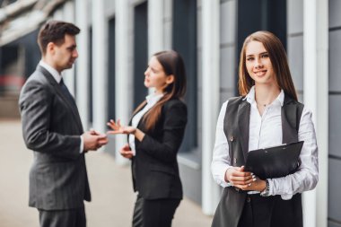 Klasörlü gülümseyen kadına odaklanarak iş planlayan iş ortakları grubu