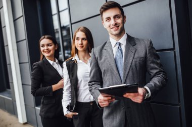 Ofis binasının yanında duran üç iş adamı