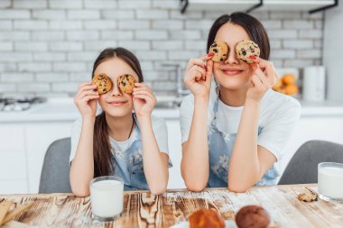 İki kız kardeş kekler ve süt içerken gülümseyen