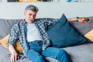 evde kanepede oturan kıdemli adam, ön plana odaklanmak