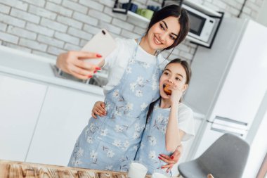kız kardeşler mutfakta birlikte yemek pişirip selfie çekerken 