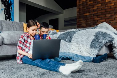 Mutlu çocuklar dizüstü bilgisayar kullanarak ve çay içme, yatakta yatan dedesi karşı