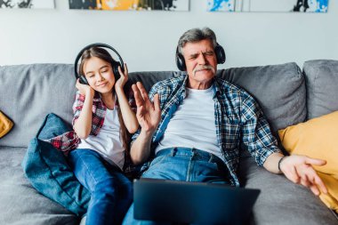 torun ve büyükbaba kanepede otururken dijital tablette müzik dinliyor