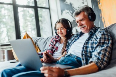 torun ve büyükbaba kanepede otururken dijital tablette müzik dinliyor