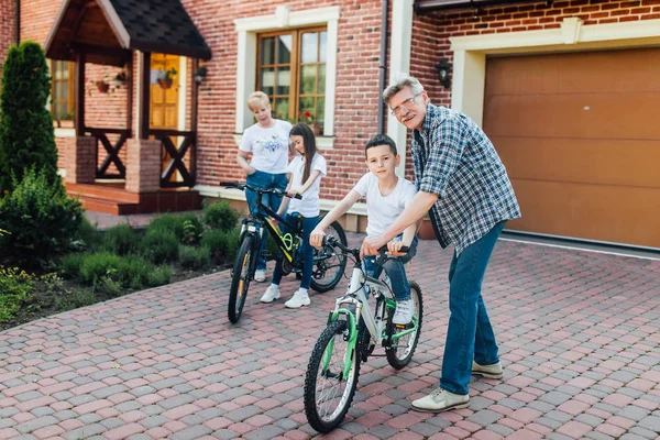 Abuelos Felices Enseñando Los Nietos Montar Bicicleta —  Fotos de Stock