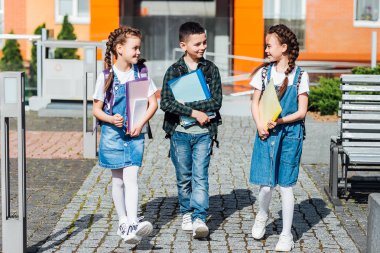 İlkokul öğrencileri okul bahçesinde konuşuyor