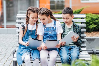 Dijital tablet kullanan üç sevimli çocuk, seçici odak