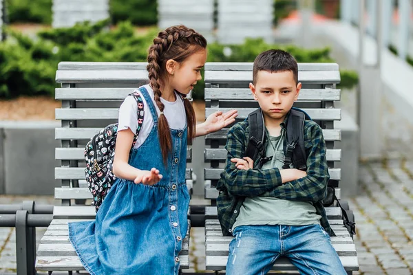 Dos Niños Con Mochilas Sentados Banco Cerca Escuela Hablando Enfoque — Foto de Stock