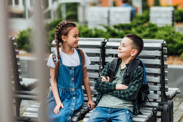 Duas Crianças Com Mochilas Sentadas Banco Perto Escola Conversando Foco — Fotografia de Stock