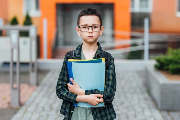 little boy in glasses with book and bag, focus on foreground