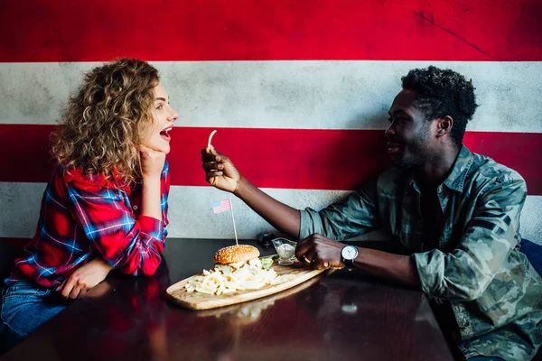 woman resting in bar with man, talking, laughing, eating fast food