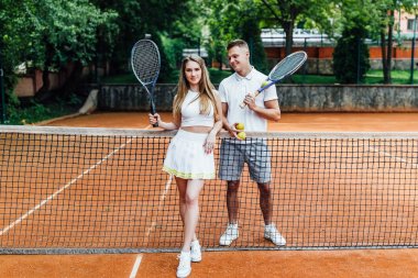 Sahada ayakta tenis raketleri ile genç Çift  