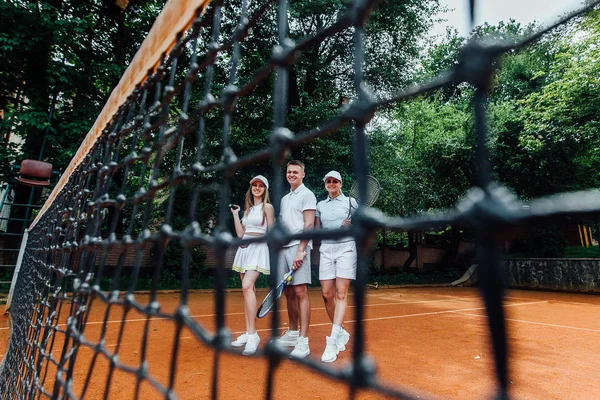 Tennis players team holding rackets after match on tennis court