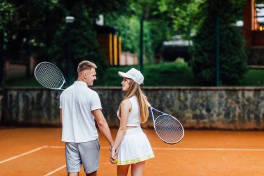 Tenis kortunda birbirlerine bakan genç çift. 