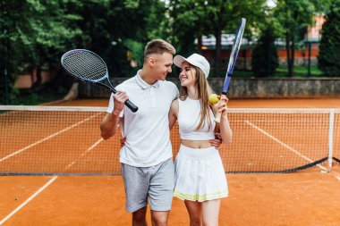 Kil kortunda tenis hocasıyla antrenman yapan genç bir kadın.