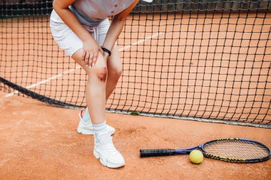 kırmızı tenis kortu üzerinde diz ağrısı muzdarip iken kadının kırpılmış görünümü 