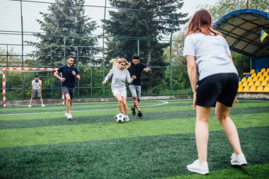 Genç erkek ve kadın açık havada futbol oyunu oynuyor