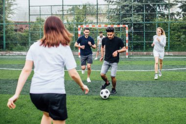 Genç erkek ve kadın açık havada futbol oyunu oynuyor