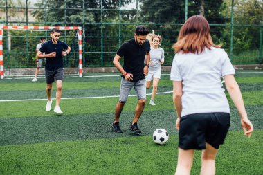 Genç erkek ve kadın açık havada futbol oyunu oynuyor