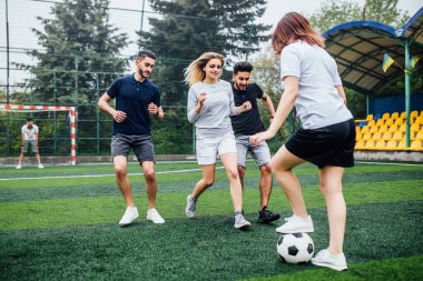 Genç erkek ve kadın açık havada futbol oyunu oynuyor