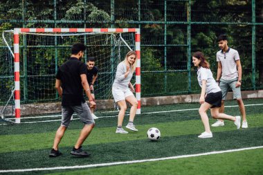 Genç erkek ve kadın açık havada futbol oyunu oynuyor