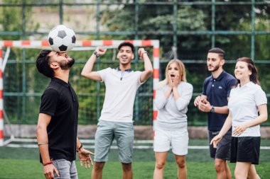 futbol sahasında arkadaşlar, ön planda topu ile adam