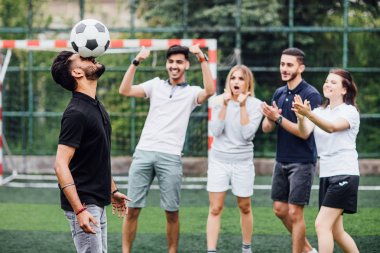 Kafa yakan futbolcu, arka planda arkadaşlar